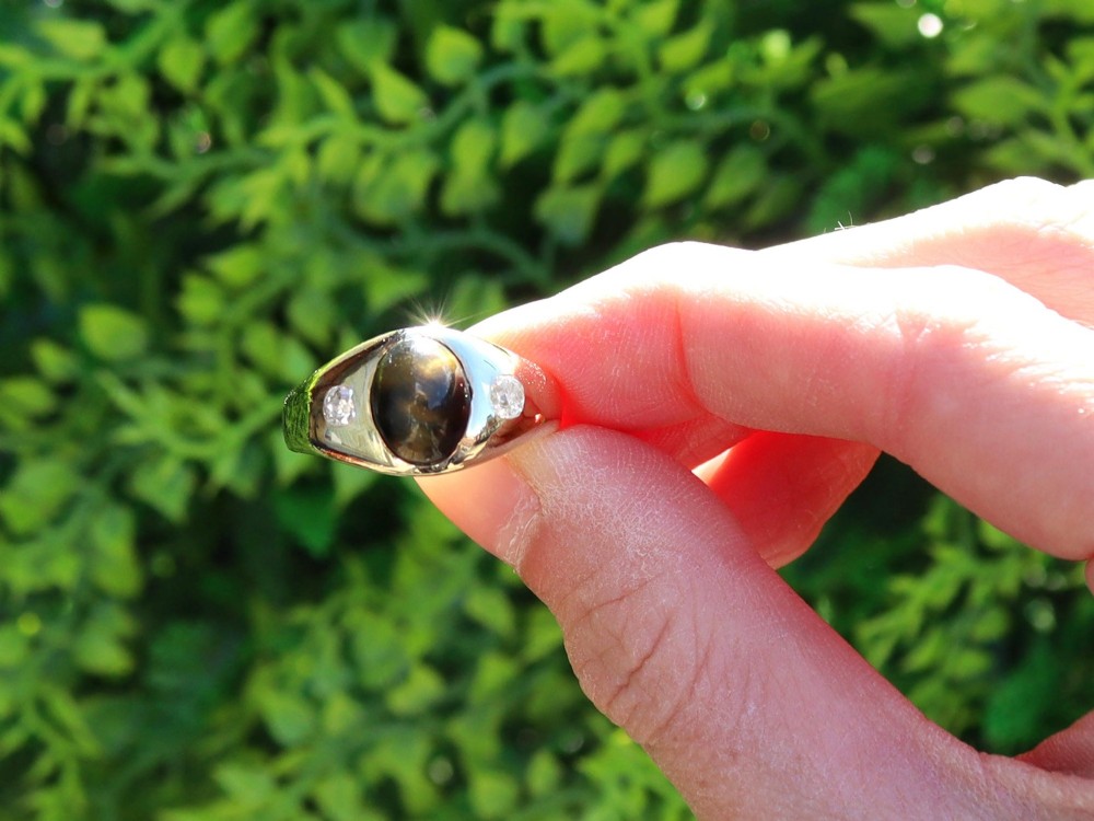 An 18ct yellow gold ring set with a central oval cabochon tigers eye stone flanked by two flush-set diamonds. View II