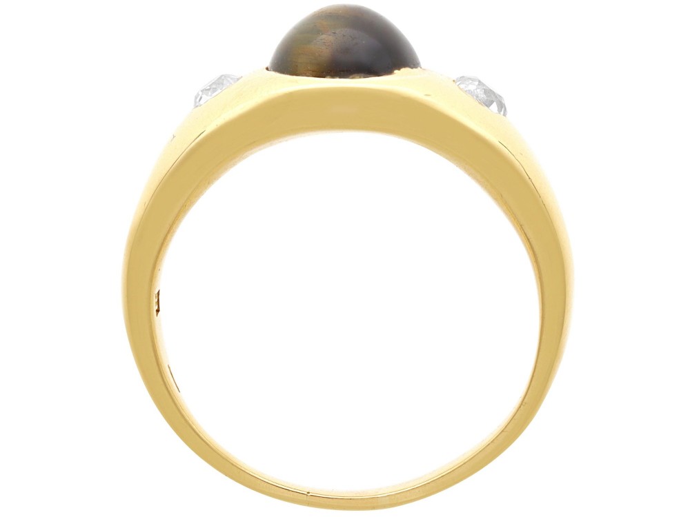 An 18ct yellow gold ring set with a central oval cabochon tigers eye stone flanked by two flush-set diamonds. View VII