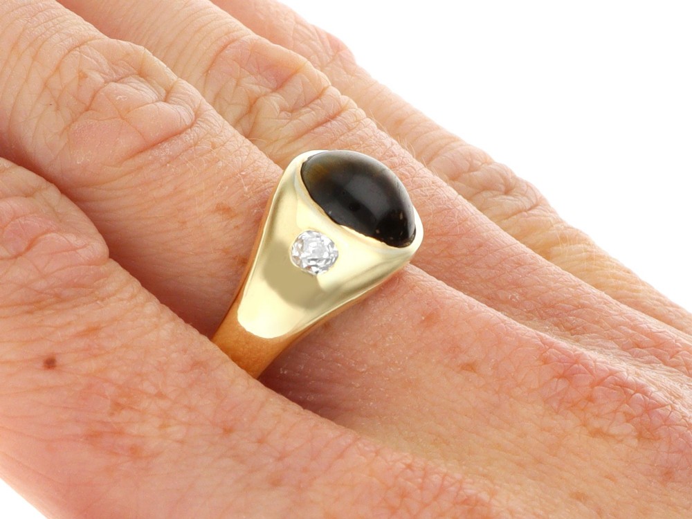 An 18ct yellow gold ring set with a central oval cabochon tigers eye stone flanked by two flush-set diamonds. View X