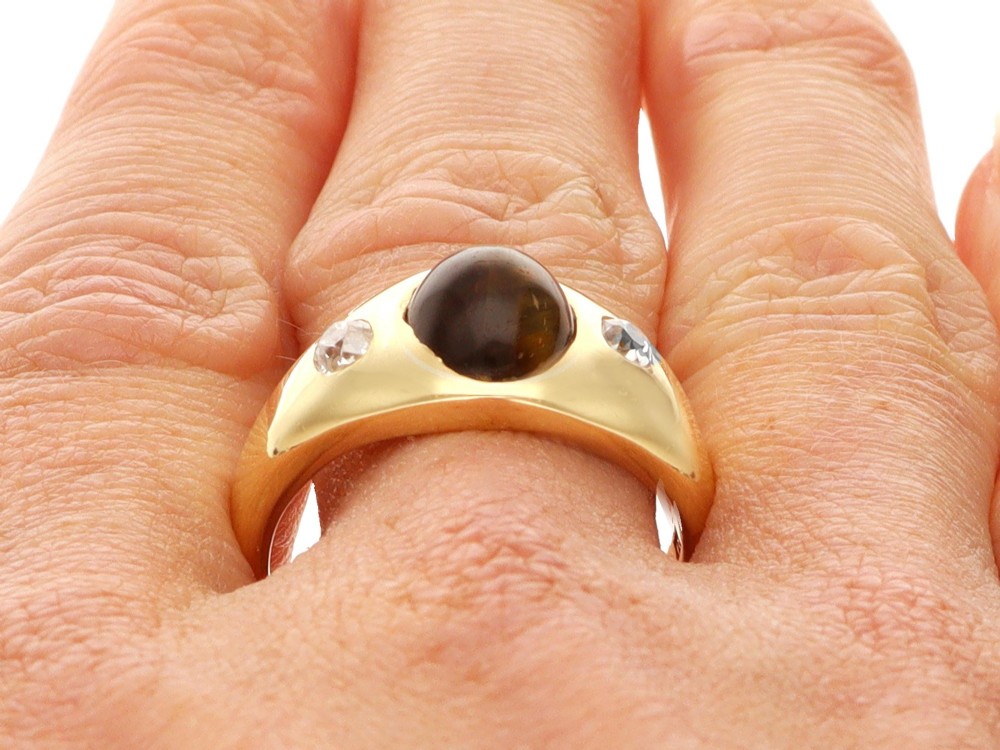 An 18ct yellow gold ring set with a central oval cabochon tigers eye stone flanked by two flush-set diamonds. View XI