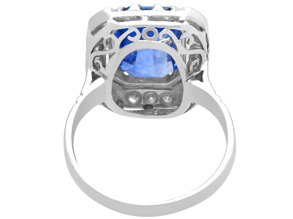An Art Deco 18ct white gold ring featuring a central octagonal step-cut blue Ceylon sapphire surrounded by a geometric diamond halo with milgrain details. View VII