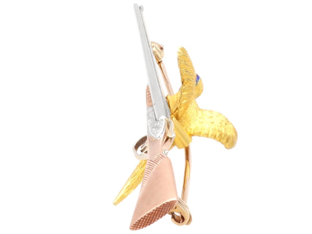 A vintage 9ct gold brooch depicting a flying pheasant with a red and green enamelled head positioned alongside a shotgun. View VIII