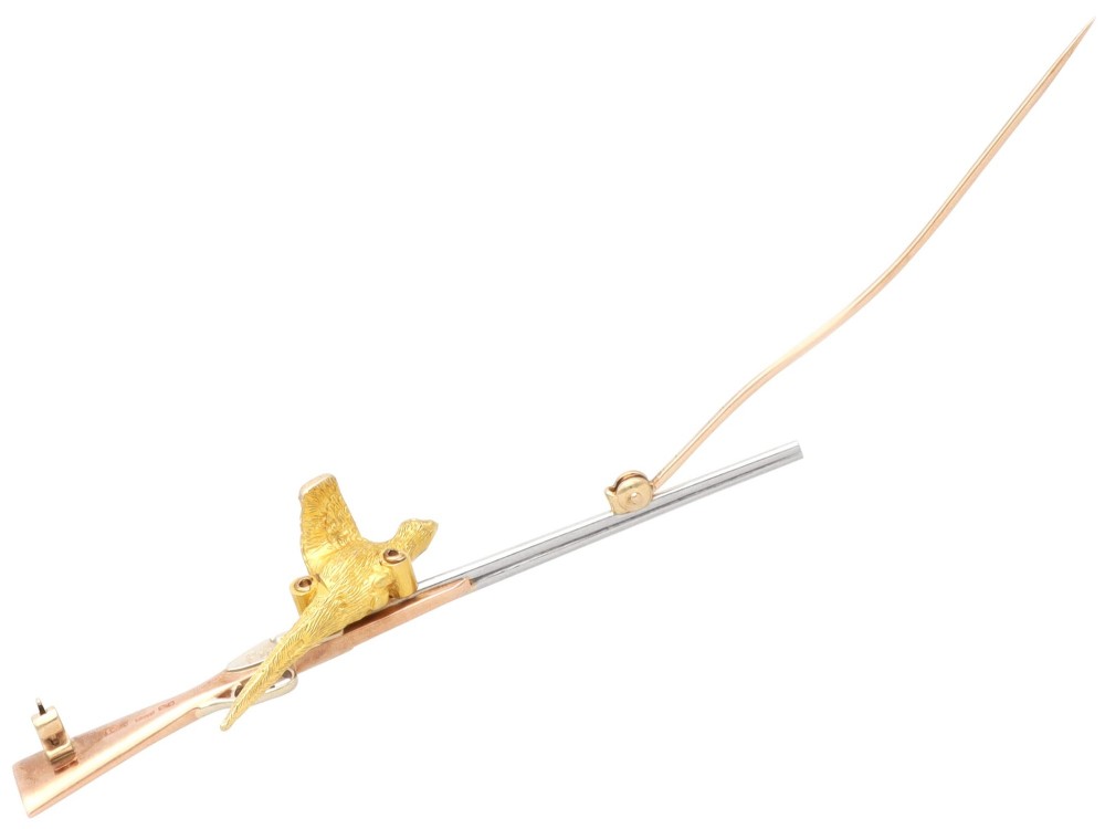 A vintage 9ct gold brooch depicting a flying pheasant with a red and green enamelled head positioned alongside a shotgun. View X