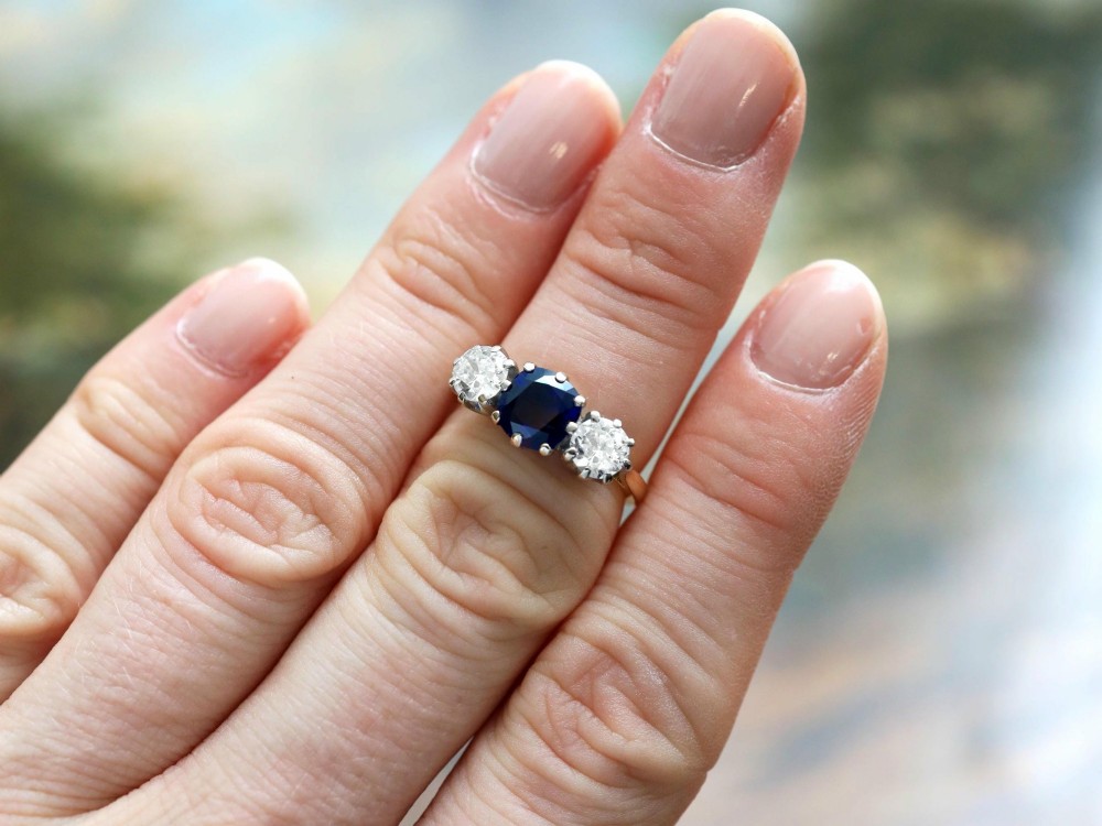 An antique 18ct yellow gold trilogy ring featuring a cushion-shaped blue sapphire flanked by two brilliant-cut diamonds in claw settings. View III