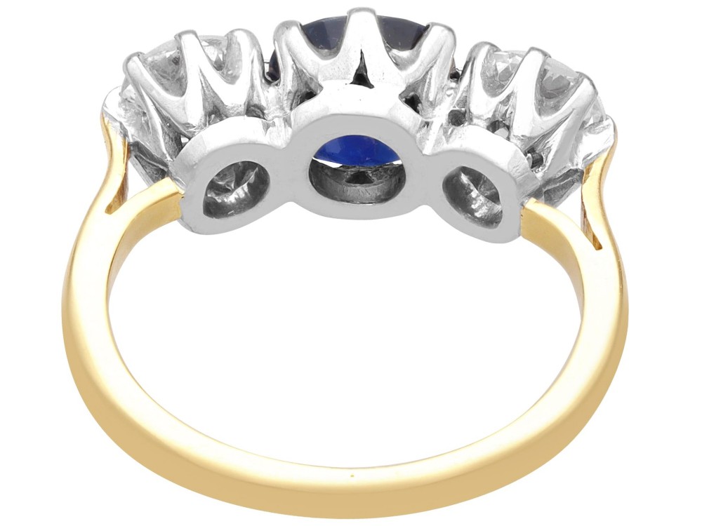 An antique 18ct yellow gold trilogy ring featuring a cushion-shaped blue sapphire flanked by two brilliant-cut diamonds in claw settings. View IX