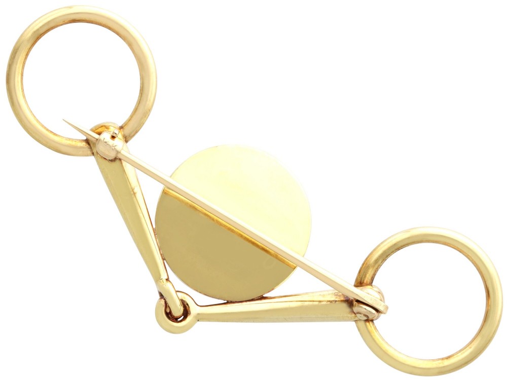 An antique 14ct yellow gold brooch designed as an equestrian snaffle bit with a central round reverse intaglio rock crystal depicting a painted fox mask. View VII