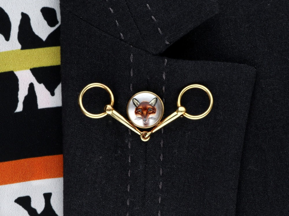 An antique 14ct yellow gold brooch designed as an equestrian snaffle bit with a central round reverse intaglio rock crystal depicting a painted fox mask. View X