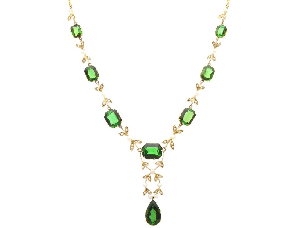 A late Victorian 14ct yellow gold necklace featuring emerald-cut green tourmalines connected by seed pearl foliate links and terminating in a pear-cut green tourmaline drop pendant.
