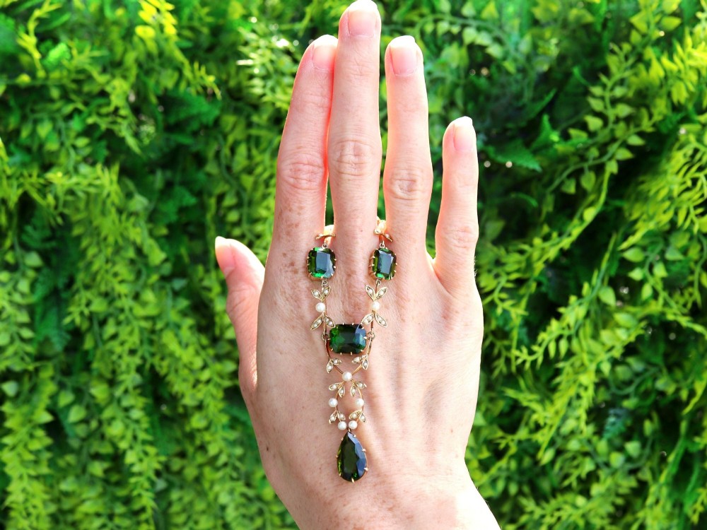 A late Victorian 14ct yellow gold necklace featuring emerald-cut green tourmalines connected by seed pearl foliate links and terminating in a pear-cut green tourmaline drop pendant. View II