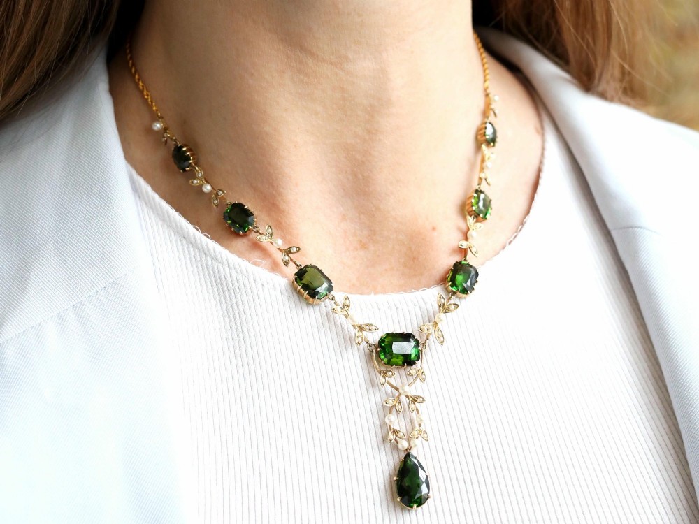 A late Victorian 14ct yellow gold necklace featuring emerald-cut green tourmalines connected by seed pearl foliate links and terminating in a pear-cut green tourmaline drop pendant. View III