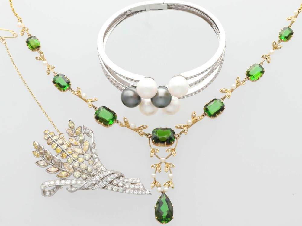 A late Victorian 14ct yellow gold necklace featuring emerald-cut green tourmalines connected by seed pearl foliate links and terminating in a pear-cut green tourmaline drop pendant. View VI