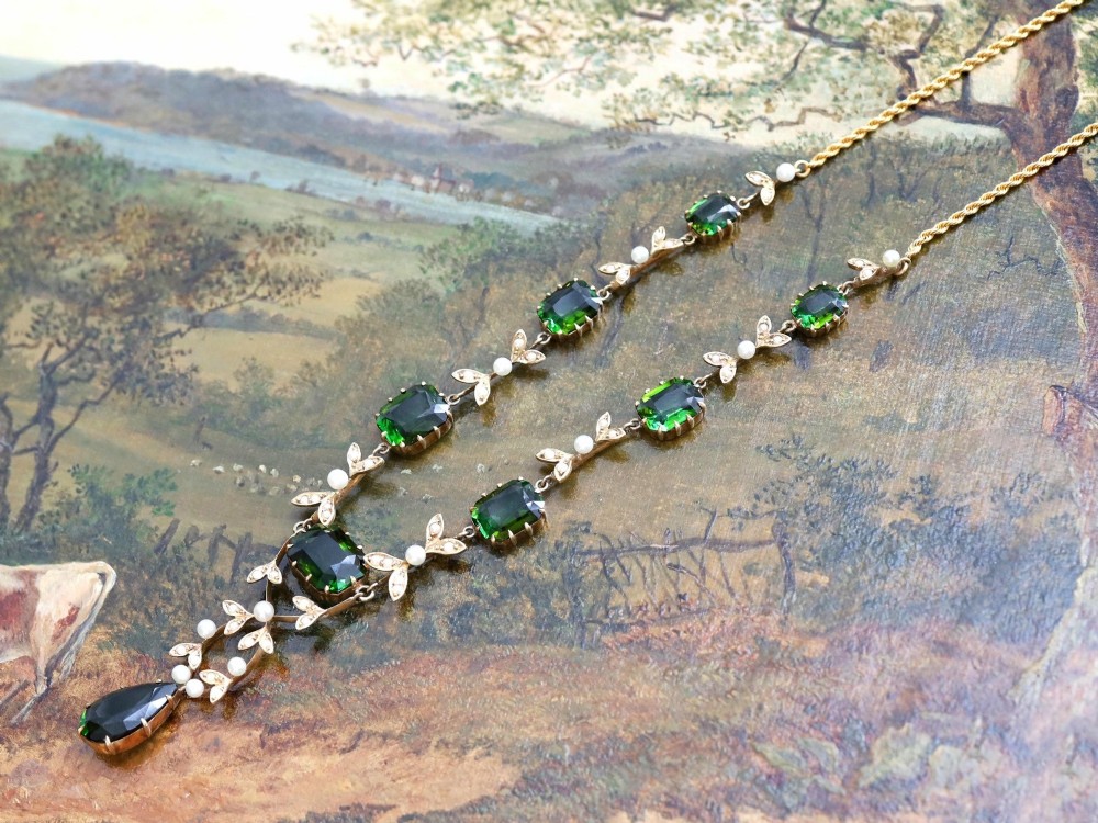 A late Victorian 14ct yellow gold necklace featuring emerald-cut green tourmalines connected by seed pearl foliate links and terminating in a pear-cut green tourmaline drop pendant. View VII