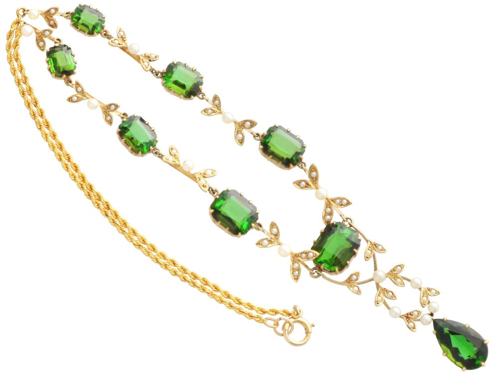 A late Victorian 14ct yellow gold necklace featuring emerald-cut green tourmalines connected by seed pearl foliate links and terminating in a pear-cut green tourmaline drop pendant. View IX