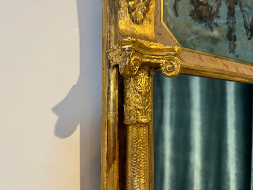 An early 19th-century Regency giltwood pier mirror featuring reeded side pilasters, a ball-encrusted cornice, and a decorative reverse-painted verre eglomise top panel. View III