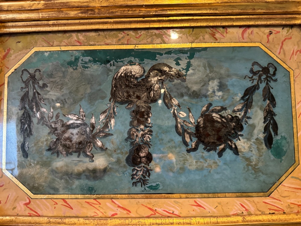 An early 19th-century Regency giltwood pier mirror featuring reeded side pilasters, a ball-encrusted cornice, and a decorative reverse-painted verre eglomise top panel. View V