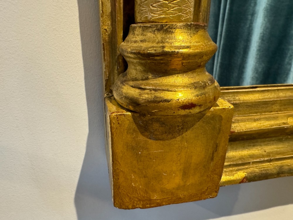 An early 19th-century Regency giltwood pier mirror featuring reeded side pilasters, a ball-encrusted cornice, and a decorative reverse-painted verre eglomise top panel. View VI
