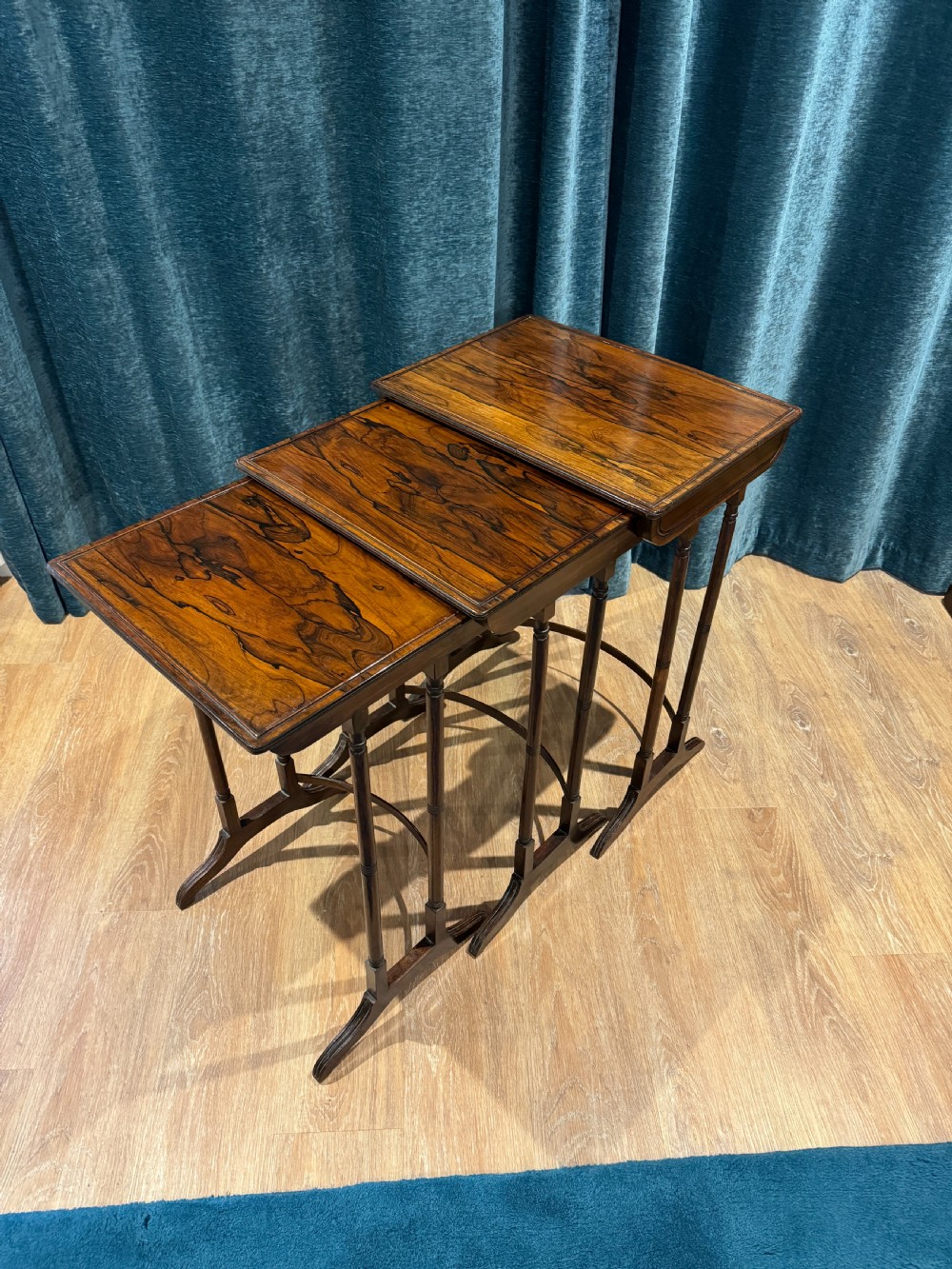 A set of three graduated Regency rosewood nesting side tables with slender turned legs and curved stretchers.