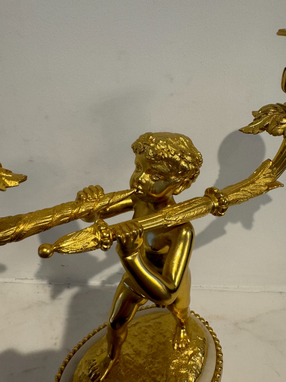 A pair of 19th-century French gilt bronze and white marble two-light candelabra featuring sculpted cherub figures supporting foliate candle branches. View VII