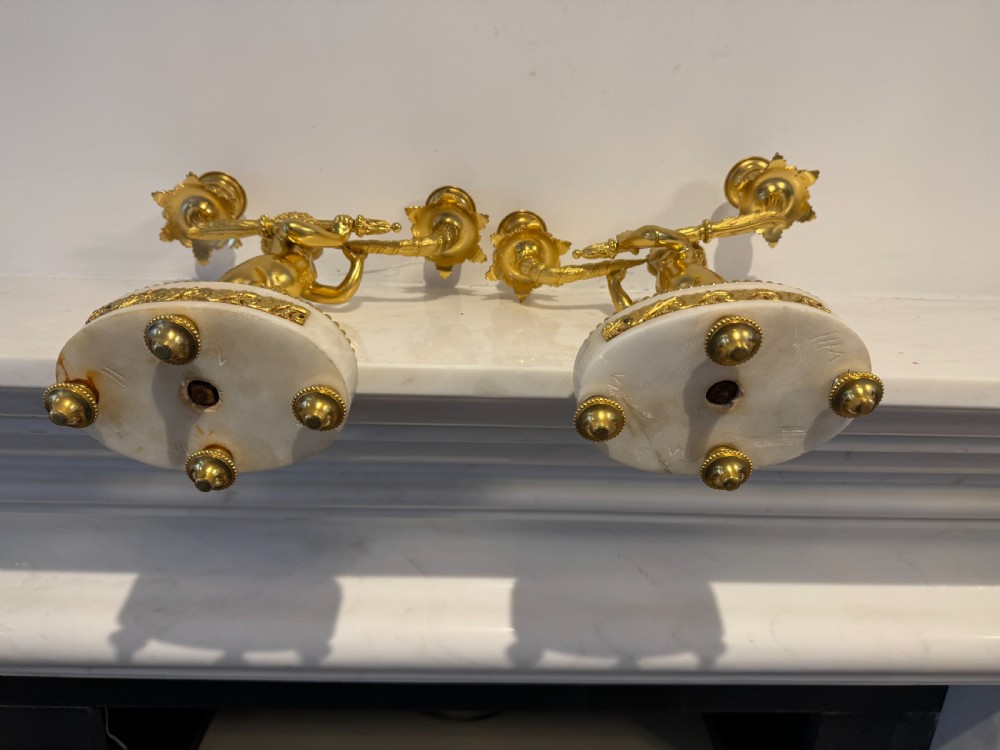 A pair of 19th-century French gilt bronze and white marble two-light candelabra featuring sculpted cherub figures supporting foliate candle branches. View VIII