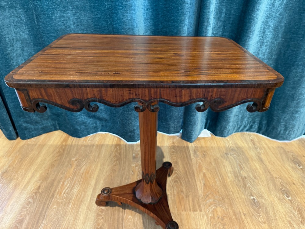 A Regency rosewood side table featuring a crossbanded rectangular top, a carved scrolled apron, and a central pedestal column supported by a triform base on scroll feet. View II
