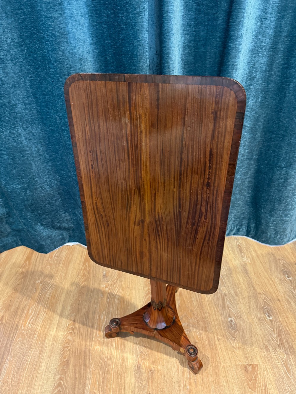 A Regency rosewood side table featuring a crossbanded rectangular top, a carved scrolled apron, and a central pedestal column supported by a triform base on scroll feet. View IV