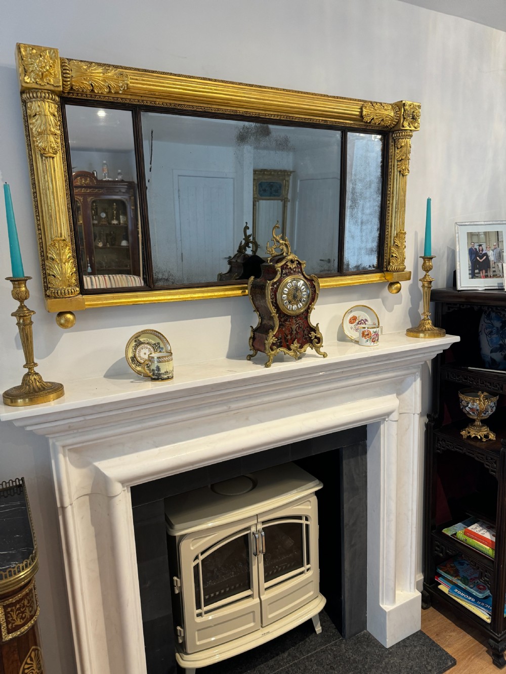 A wide Regency giltwood tripartite overmantel mirror featuring side fluted columns and carved leaf accents. View II