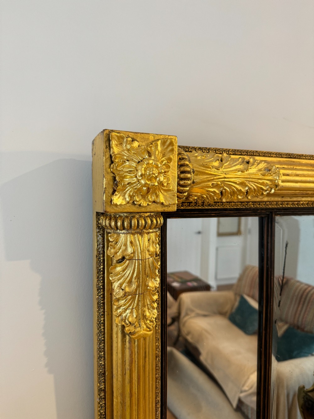 A wide Regency giltwood tripartite overmantel mirror featuring side fluted columns and carved leaf accents. View III