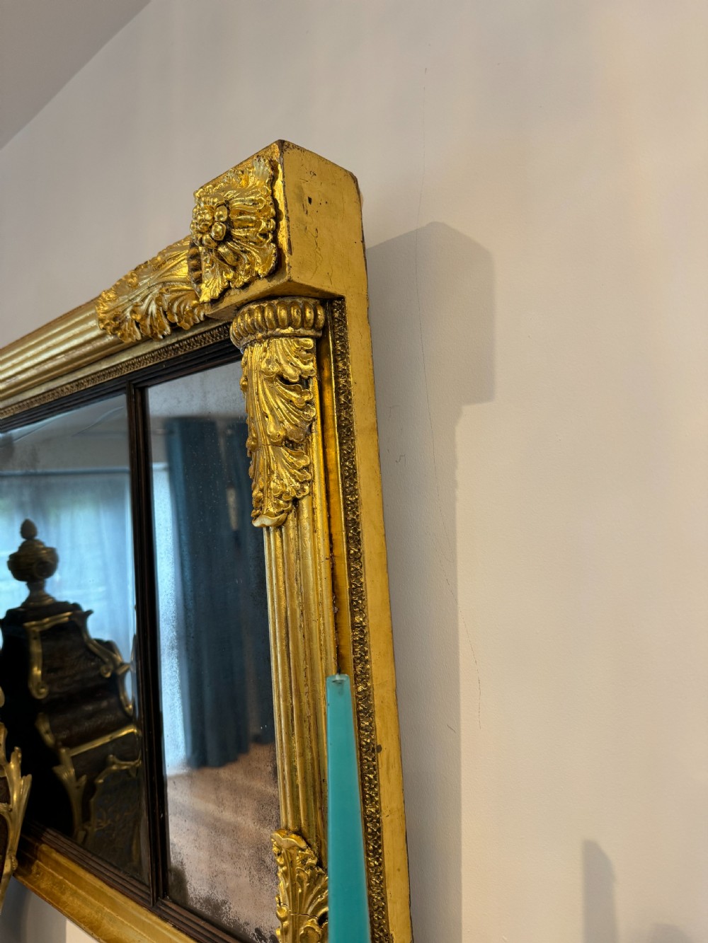 A wide Regency giltwood tripartite overmantel mirror featuring side fluted columns and carved leaf accents. View V
