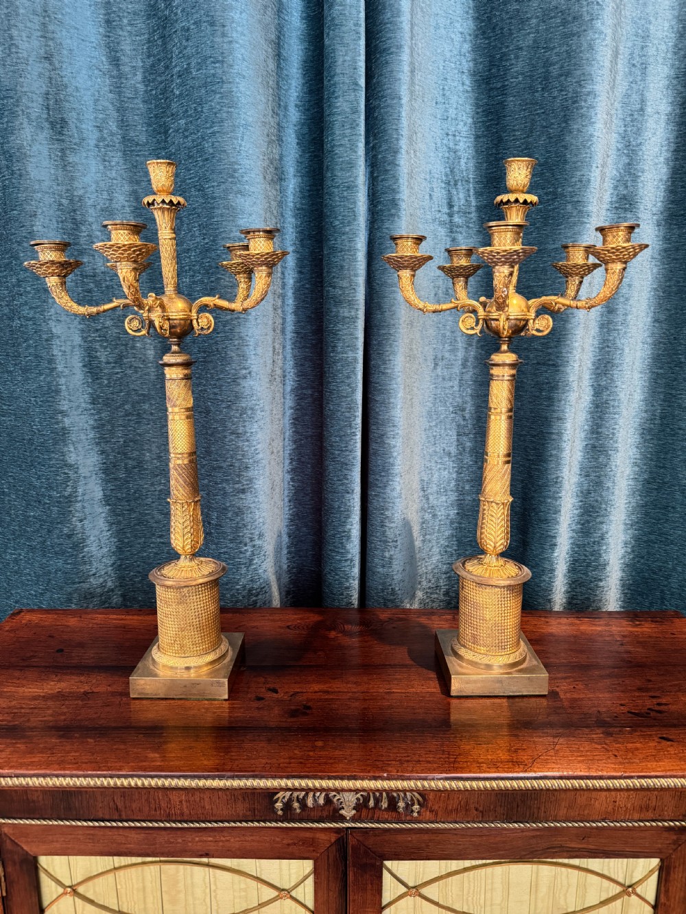 A pair of French Empire ormolu five-branch candelabra featuring intricate engine-turned decoration and square plinth bases. View II