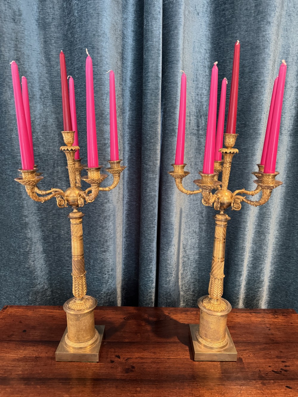 A pair of French Empire ormolu five-branch candelabra featuring intricate engine-turned decoration and square plinth bases.