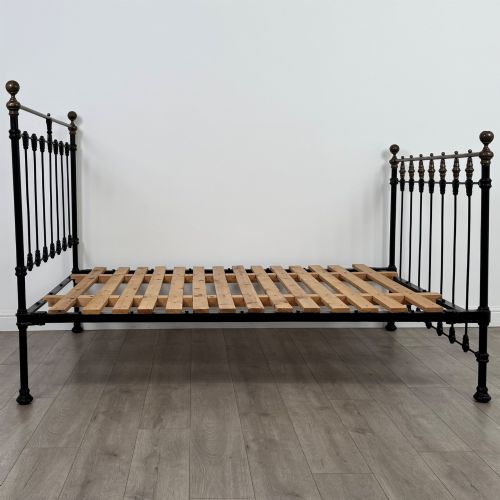 fig 2. A 19th-century double bedstead featuring a black iron spindle frame with polished brass top rails and finials.