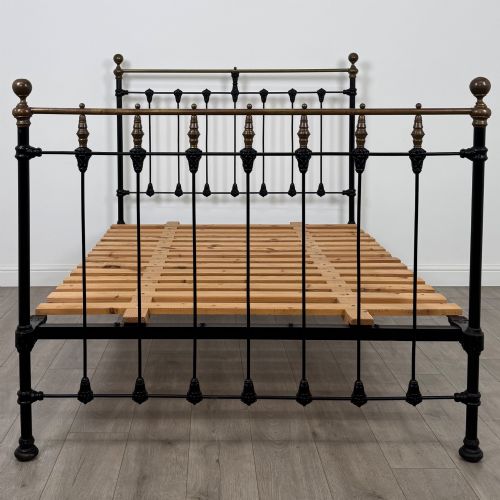 fig 3. A 19th-century double bedstead featuring a black iron spindle frame with polished brass top rails and finials.