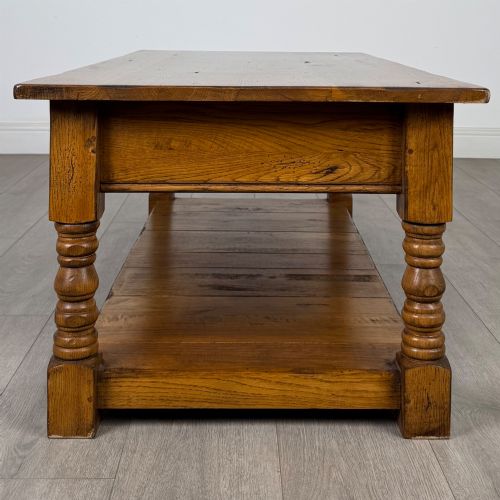fig 2. A low rectangular oak coffee table featuring two drawers with metal drop handles, turned legs, and an open lower plank shelf.