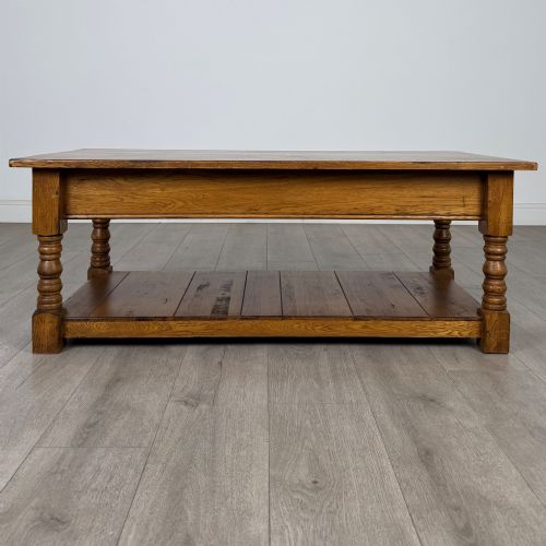 fig 4. A low rectangular oak coffee table featuring two drawers with metal drop handles, turned legs, and an open lower plank shelf.