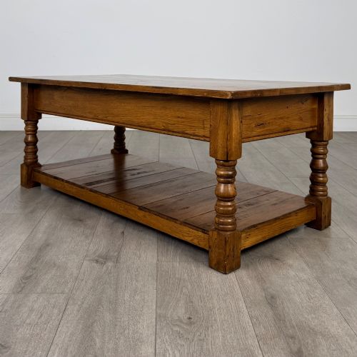 fig 5. A low rectangular oak coffee table featuring two drawers with metal drop handles, turned legs, and an open lower plank shelf.