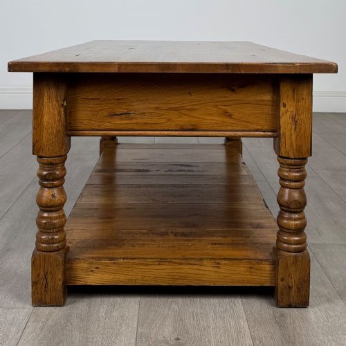 fig 6. A low rectangular oak coffee table featuring two drawers with metal drop handles, turned legs, and an open lower plank shelf.
