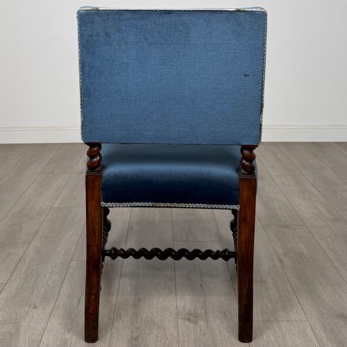 fig 3. A nineteenth-century dark oak armchair featuring barley twist legs and stretchers, blue fabric upholstery, and brass front castors.