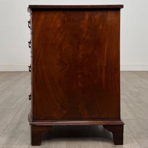 fig 2. A twentieth-century mahogany kneehole desk featuring a serpentine front, multiple drawers with brass swan-neck handles, and bracket feet.