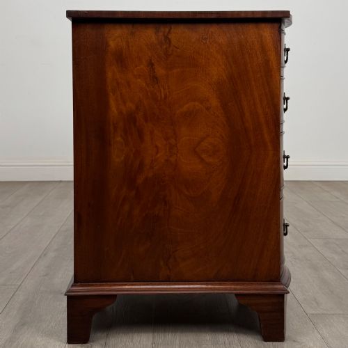 fig 6. A twentieth-century mahogany kneehole desk featuring a serpentine front, multiple drawers with brass swan-neck handles, and bracket feet.