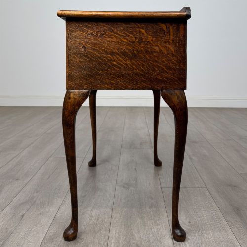 fig 2. An Edwardian oak side table featuring two front drawers with brass drop handles, a scalloped apron, and slender cabriole legs.