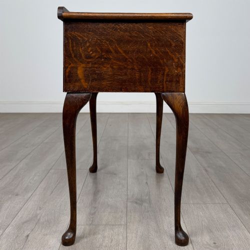 fig 6. An Edwardian oak side table featuring two front drawers with brass drop handles, a scalloped apron, and slender cabriole legs.