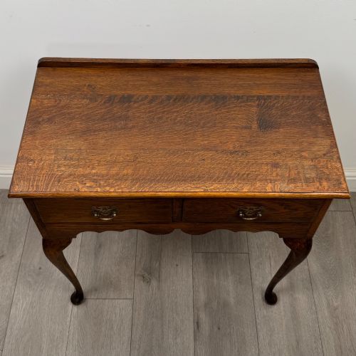 fig 8. An Edwardian oak side table featuring two front drawers with brass drop handles, a scalloped apron, and slender cabriole legs.