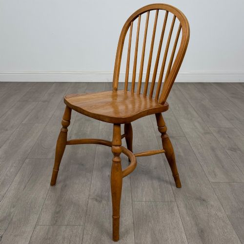 fig 1. A set of six light warm brown ash Windsor dining chairs featuring hoop backs, turned spindles, shaped wooden seats, and turned legs with stretchers.