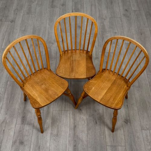 fig 6. A set of six light warm brown ash Windsor dining chairs featuring hoop backs, turned spindles, shaped wooden seats, and turned legs with stretchers.