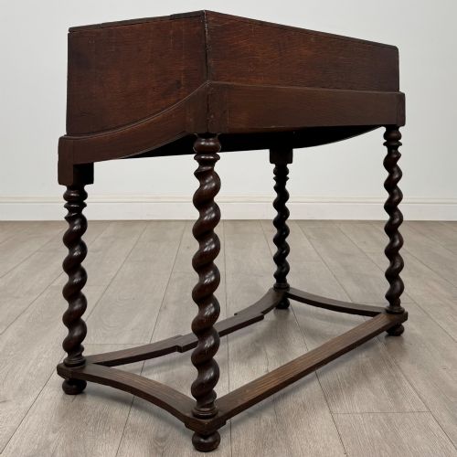 fig 3. A 19th-century dark oak box on a wooden stand featuring four spiral barley twist legs and a central brass keyhole escutcheon.