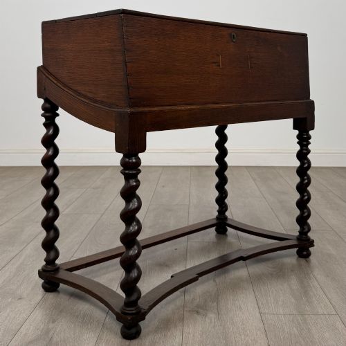 fig 7. A 19th-century dark oak box on a wooden stand featuring four spiral barley twist legs and a central brass keyhole escutcheon.