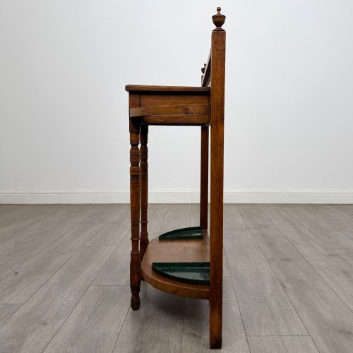 fig 2. An Edwardian golden oak hall stand with a top spindle gallery, central glove drawer with brass handle, twin umbrella rail apertures, and metal drip trays on the lower shelf.