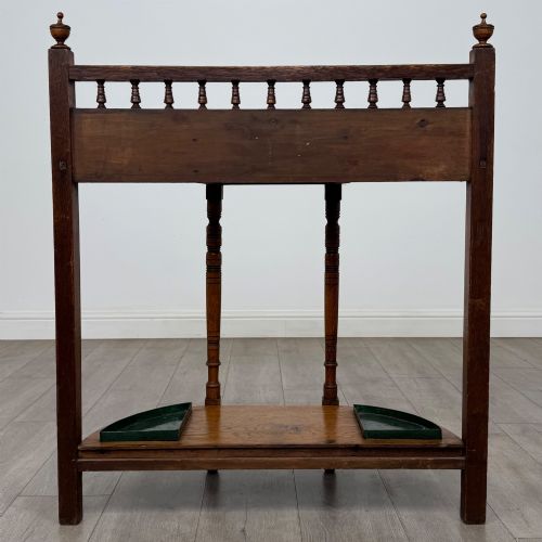fig 4. An Edwardian golden oak hall stand with a top spindle gallery, central glove drawer with brass handle, twin umbrella rail apertures, and metal drip trays on the lower shelf.