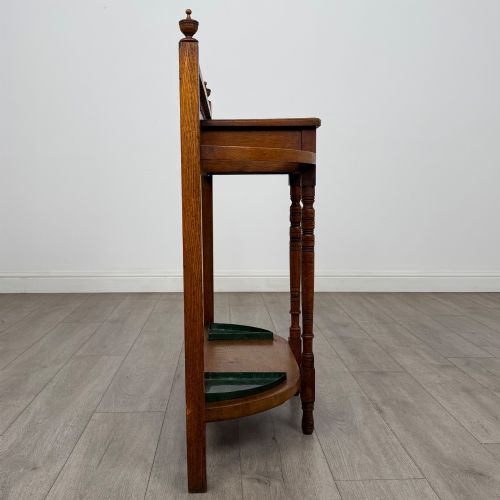 fig 6. An Edwardian golden oak hall stand with a top spindle gallery, central glove drawer with brass handle, twin umbrella rail apertures, and metal drip trays on the lower shelf.