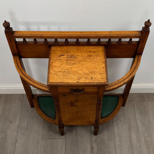 fig 8. An Edwardian golden oak hall stand with a top spindle gallery, central glove drawer with brass handle, twin umbrella rail apertures, and metal drip trays on the lower shelf.